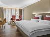 Zimmer Komtess im Wellnesshotel Churfürstenhof: Doppelbett, rote Sessel und Schreibtisch in warmen Farben