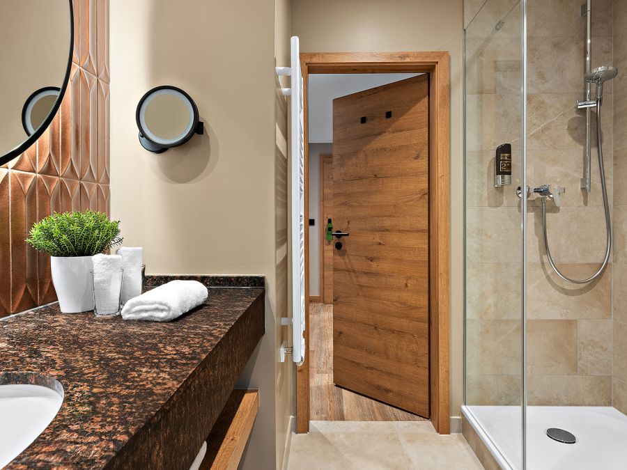 Badezimmer im Prinzess-Zimmer des Wellnesshotels Churfürstenhof mit Waschtisch, rundem Spiegel und Glasdusche