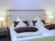 Doppelbett mit heller Bettwäsche und Nachttischlampen im Zimmer Baroness, Hotel Churfürstenhof Bad Birnbach