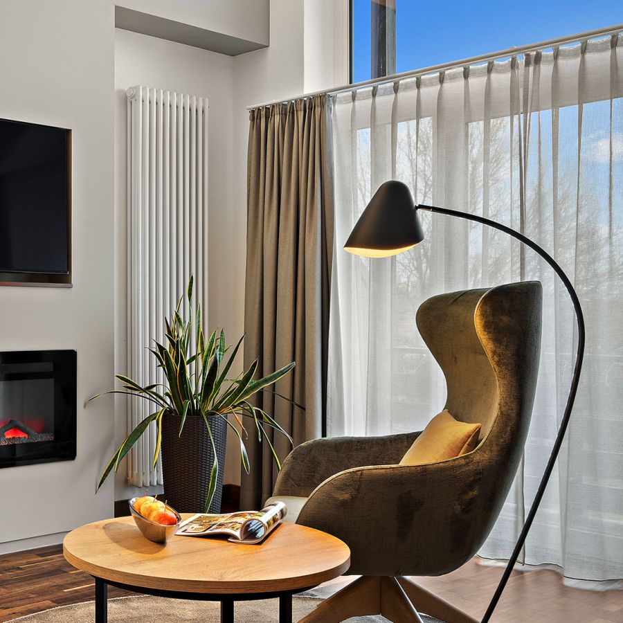Wohnbereich der Komfort-Suite im Wellnesshotel Churfürstenhof mit Elektrokamin, TV, Sessel und Stehlampe