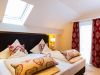 Gemütliches Doppelbett mit Herzkissen unter Dachschräge im Bad Birnbacher Chalet des Hotel Churfürstenhof
