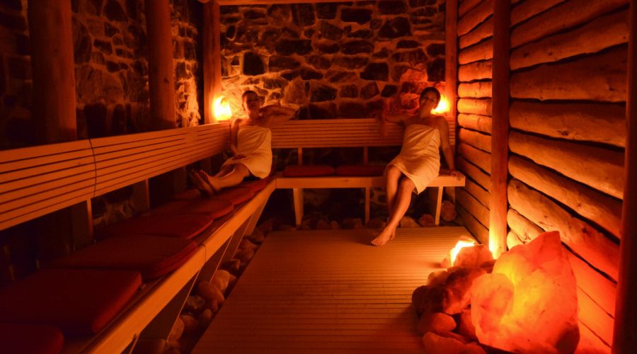 Zwei Frauen entspannen in der rustikalen Steinsauna mit leuchtenden Salzkristallen im Hotel Churfürstenhof