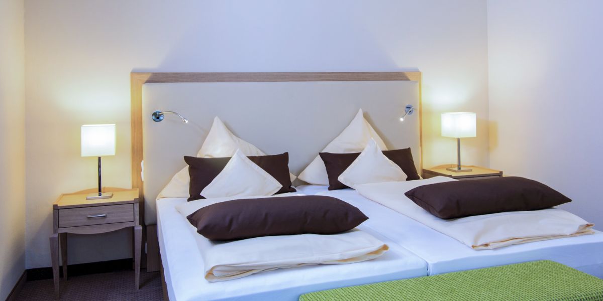 Doppelbett mit heller Bettwäsche und Nachttischlampen im Zimmer Baroness, Hotel Churfürstenhof Bad Birnbach