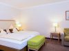 Doppelbett mit weißer Bettwäsche und grüner Sitzbank im Zimmer Baroness, Hotel Churfürstenhof Bad Birnbach