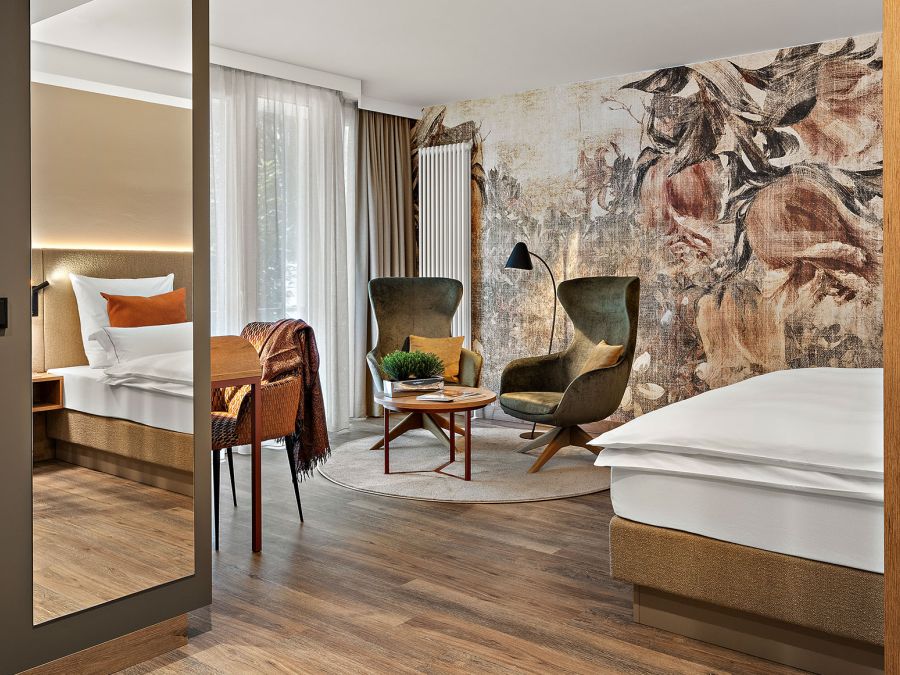 Zimmer Prinzess im Wellnesshotel Churfürstenhof mit floraler Wandgestaltung, grünen Sesseln und großem Spiegel