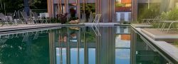 Außenpool des Hotels Churfürstenhof am Abend, das Badehaus spiegelt sich im Wasser