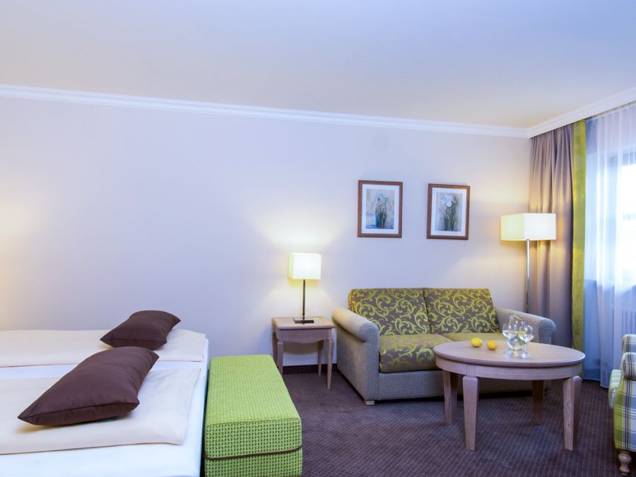 Hotelzimmer Baroness im Churfürstenhof Bad Birnbach mit Doppelbett, Sofa und grünen Farbakzenten