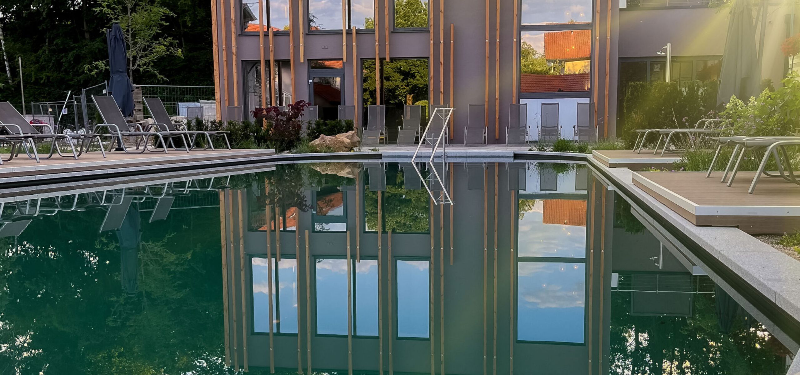 Außenpool des Hotels Churfürstenhof am Abend, das Badehaus spiegelt sich im Wasser