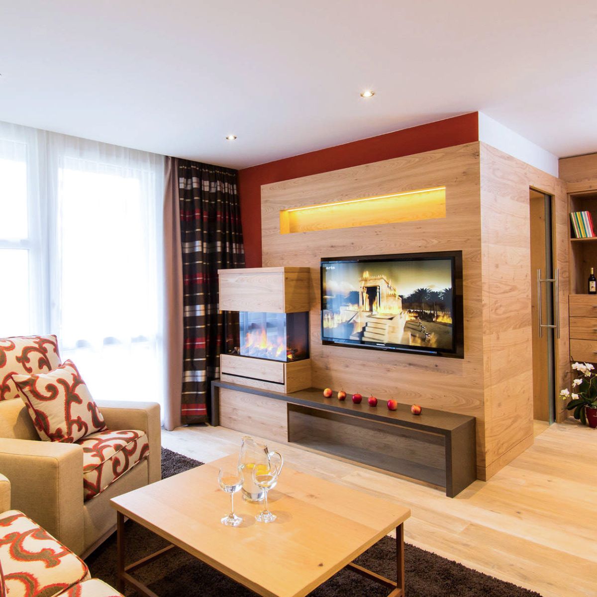 Wohnzimmer der Suite Royal im Churfürstenhof Bad Birnbach mit Sofa, Kamin und TV-Wand aus Holz