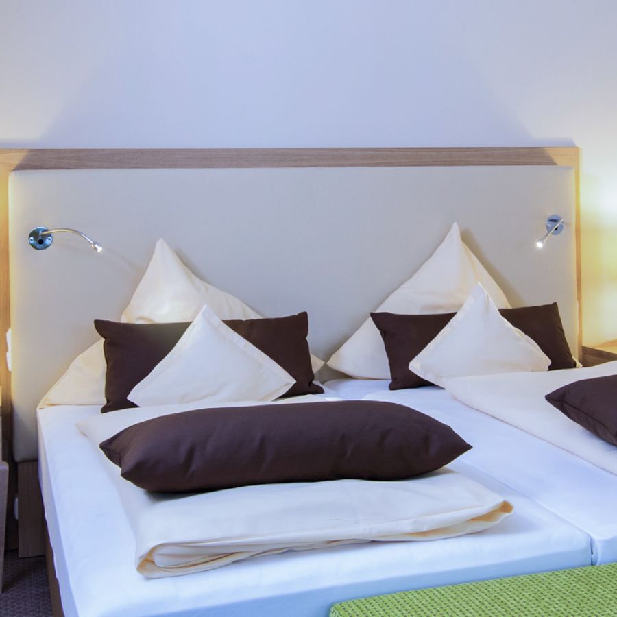 Doppelbett mit heller Bettwäsche und Nachttischlampen im Zimmer Baroness, Hotel Churfürstenhof Bad Birnbach