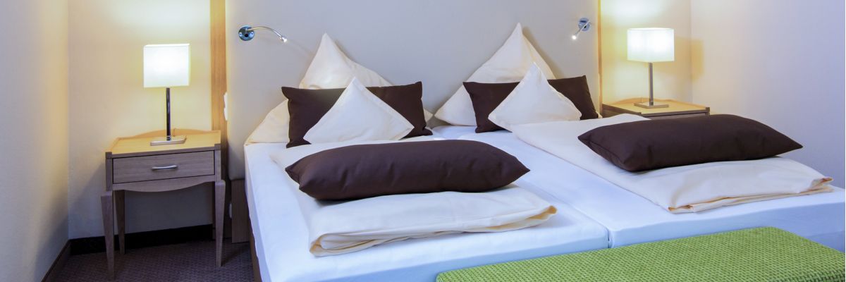 Doppelbett mit heller Bettwäsche und Nachttischlampen im Zimmer Baroness, Hotel Churfürstenhof Bad Birnbach
