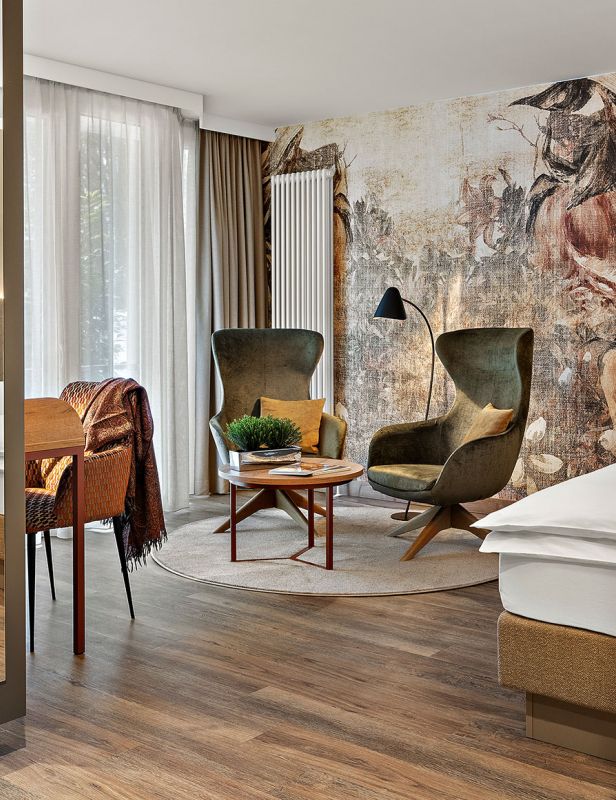Zimmer Prinzess im Wellnesshotel Churfürstenhof mit floraler Wandgestaltung, grünen Sesseln und großem Spiegel