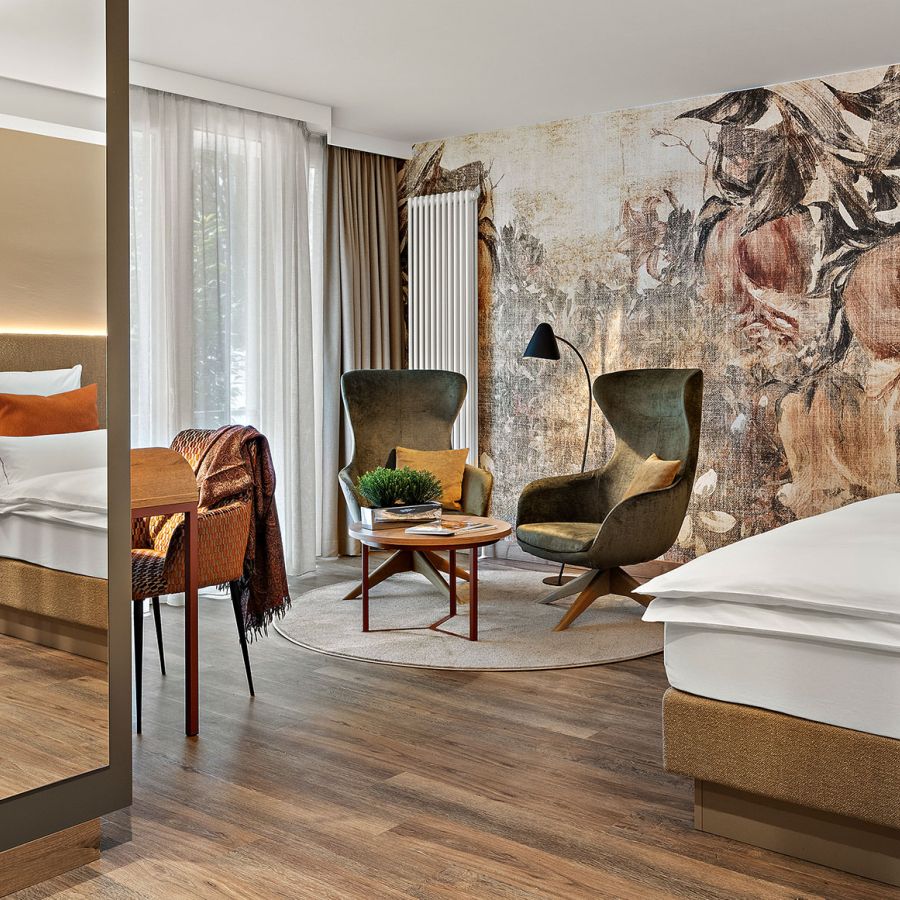Zimmer Prinzess im Wellnesshotel Churfürstenhof mit floraler Wandgestaltung, grünen Sesseln und großem Spiegel
