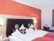 Schlafzimmer der Suite Royal im Hotel Churfürstenhof Bad Birnbach mit Doppelbett vor roter Akzentwand