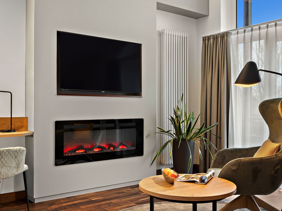 Wohnbereich der Komfort-Suite im Wellnesshotel Churfürstenhof mit Elektrokamin, TV, Sessel und Stehlampe