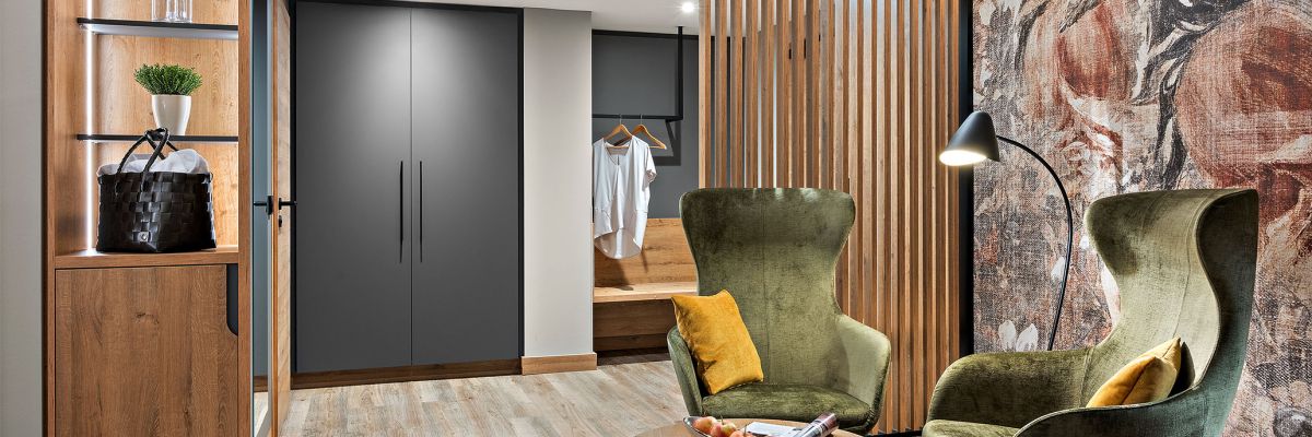 Zimmer Prinzess im Hotel Churfürstenhof Bad Birnbach mit grünen Sesseln, Holzlamellen und Garderobe