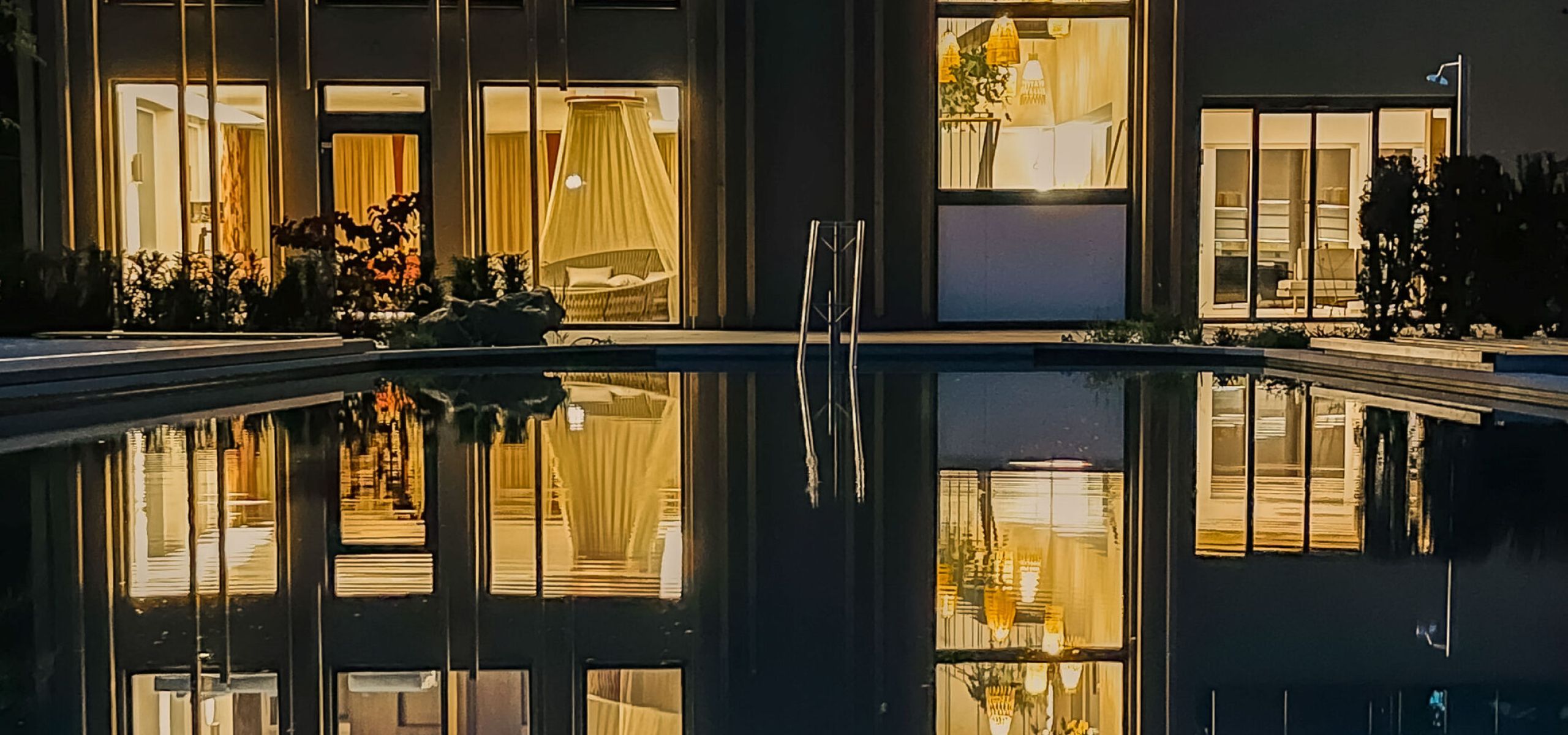 Beleuchtete Fassade des Hotel Churfürstenhof spiegelt sich abends im Außenpool