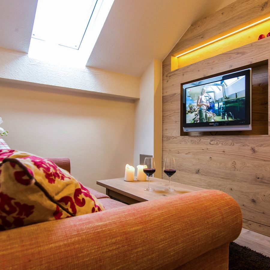 Gemütliche TV-Ecke mit Sofa, Kerzen und Rotwein im Bad Birnbacher Chalet des Hotel Churfürstenhof