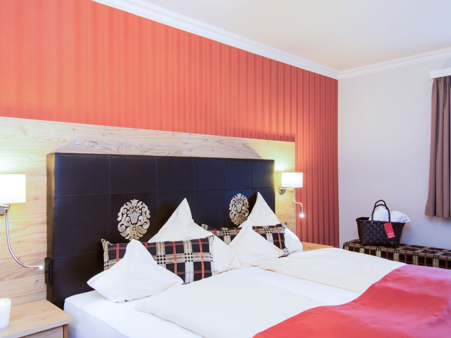 Schlafzimmer der Suite Royal im Hotel Churfürstenhof Bad Birnbach mit Doppelbett vor roter Akzentwand