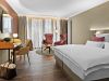 Zimmer Komtess im Wellnesshotel Churfürstenhof: Doppelbett, rote Sessel und Schreibtisch in warmen Farben