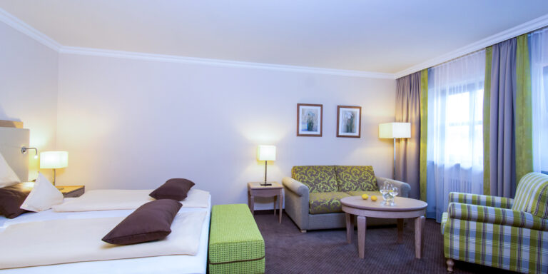 Hotelzimmer Baroness im Churfürstenhof Bad Birnbach mit Doppelbett, Sofa und grünen Farbakzenten