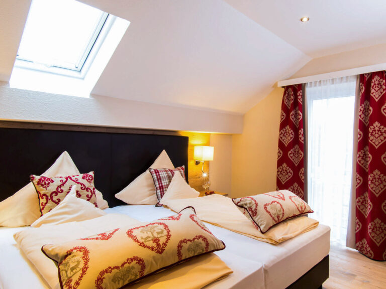 Gemütliches Doppelbett mit Herzkissen unter Dachschräge im Bad Birnbacher Chalet des Hotel Churfürstenhof