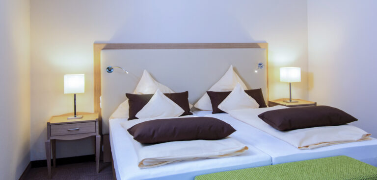 Doppelbett mit heller Bettwäsche und Nachttischlampen im Zimmer Baroness, Hotel Churfürstenhof Bad Birnbach
