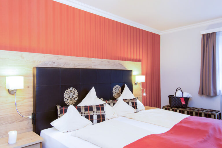 Schlafzimmer der Suite Royal im Hotel Churfürstenhof Bad Birnbach mit Doppelbett vor roter Akzentwand