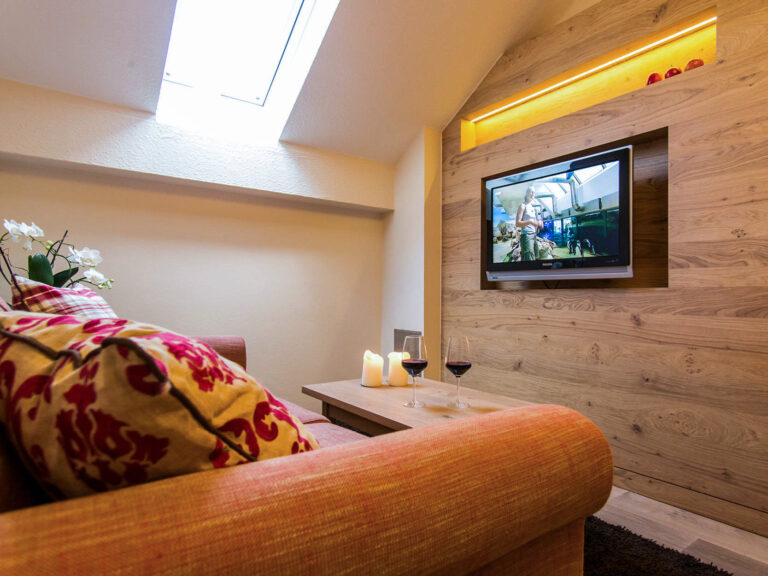 Gemütliche TV-Ecke mit Sofa, Kerzen und Rotwein im Bad Birnbacher Chalet des Hotel Churfürstenhof
