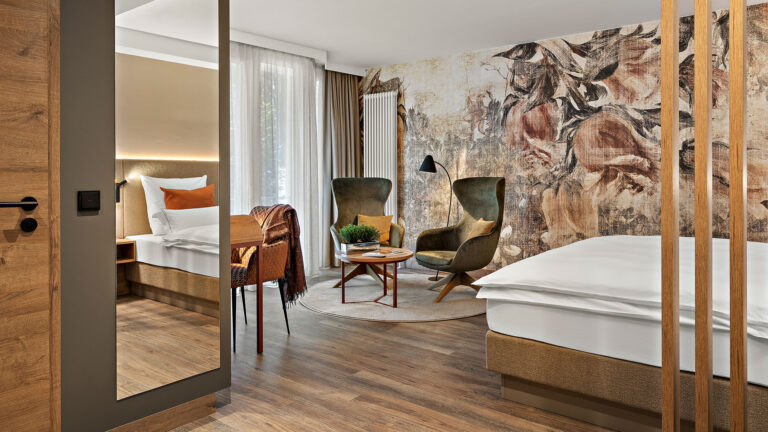 Zimmer Prinzess im Wellnesshotel Churfürstenhof mit floraler Wandgestaltung, grünen Sesseln und großem Spiegel