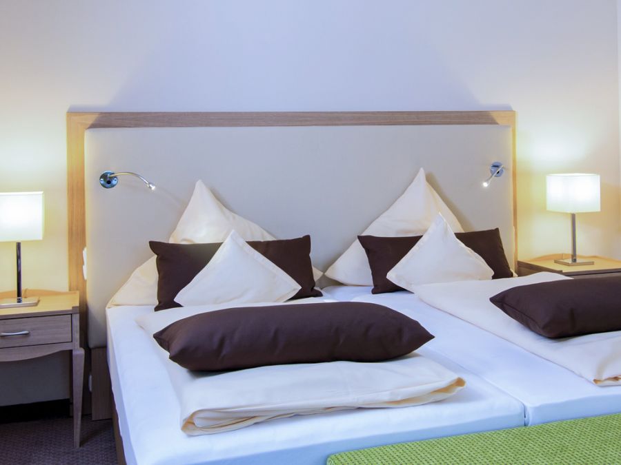 Doppelbett mit heller Bettwäsche und Nachttischlampen im Zimmer Baroness, Hotel Churfürstenhof Bad Birnbach